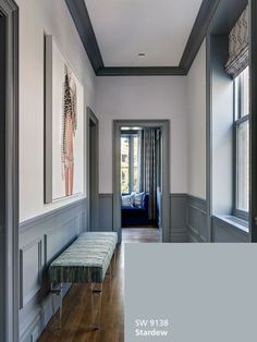 the hallway is painted in gray and has a bench on one side, along with two windows