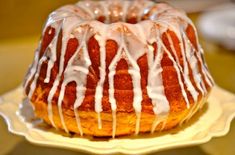 a bundt cake covered in icing on a white plate with a yellow background