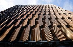 an upward view of the top of a tall building with wooden slats on it's sides