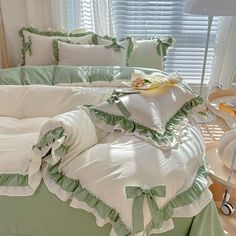 a green and white bed with ruffles on the sheets, pillows and pillow cases