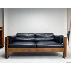 a black leather couch sitting on top of a wooden frame