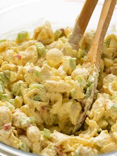 a bowl filled with macaroni salad and two wooden spoons sticking out of it