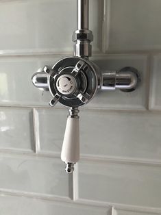 the faucet is attached to the tiled wall in the shower area, which also has an overhead sprayer