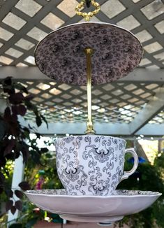 an upside down coffee cup and saucer hanging from a ceiling fixture in a garden