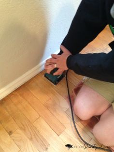 a woman kneeling down on the floor with a vacuum in her hand