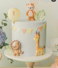 a cake decorated with animals and balloons on a table