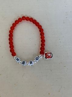 "Support your favorite firefighter with this adorable HERO bracelet. Made with glass red beads, and plastic letters surrounded by silver beads. There is a small enamel fire hat charm hanging from the side.   It stretches to fits up to a 7.5\" wrist.  Comes wrapped in a gift giving bag with tie. In stock items ship within 2-3 business days.  Custom orders can take up to 10 days. Shipping Times - Please allow 3-5  delivery in the U.S.  7-10 business days to Canada and 10-15 business days to Europe Firefighter Bracelet, Plastic Letters, Bead Charm Bracelet, Red Bead, Eye Jewelry, Jewelry Creation, Firefighter, Silver Beads, Bead Charms