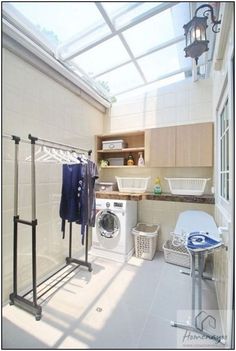 a washer and dryer sitting in a room next to a laundry basket with clothes hanging on it