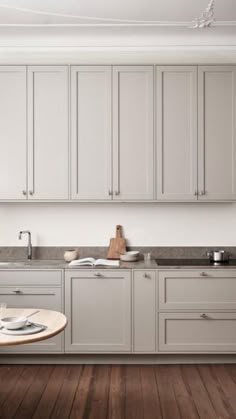 a large kitchen with white cabinets and wood flooring, along with a dining table