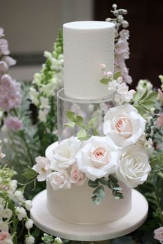 a three tiered wedding cake with flowers on top