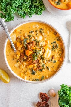 two bowls filled with soup next to some kale and lemon wedges on the side