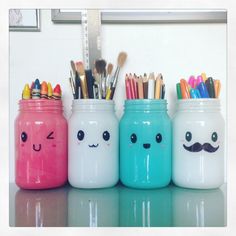 three jars with different colored pencils and pens in them, one has a face drawn on it