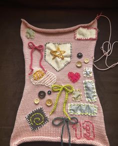 a pink knitted blanket with buttons and other things attached to the back of it