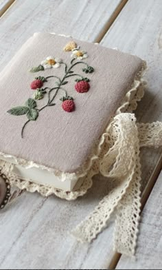 a book with some flowers on it sitting on top of a wooden table next to a button