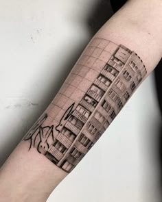 a man's arm with a cityscape tattoo on the left inner forearm