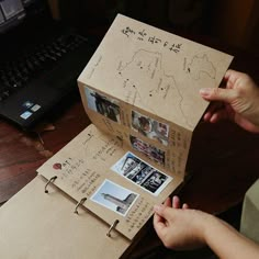 an open cardboard box with pictures and writing on it, held up by someone's hands