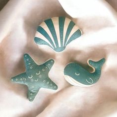 three ceramic sea animals sitting on top of a white cloth covered tablecloth with shells and seashells in the shape of stars