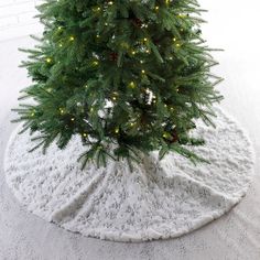 a small christmas tree in the middle of a white blanket on top of a snow covered floor