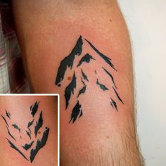 a man's arm with black ink on it and the image of a mountain