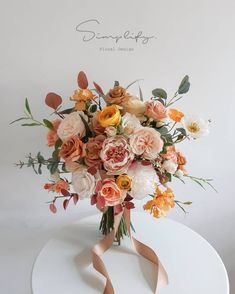 a bouquet of flowers sitting on top of a white table with a ribbon around it