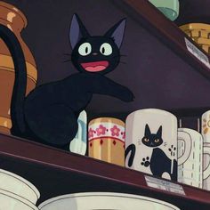 black cat sitting on top of a shelf next to coffee mugs