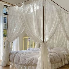 a canopy bed with white drapes and curtains