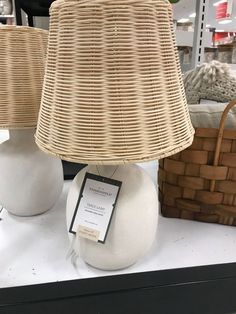 two wicker lamps sitting on top of a white table next to a brown basket