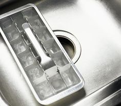 an ice tray sitting on top of a metal sink under a faucet drain