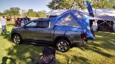 a truck with a tent attached to it parked in the grass