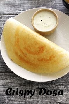 a close up of a plate of food on a wooden table with the words crispy dosa