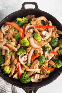 chicken stir fry in a skillet with broccoli and peppers on the side