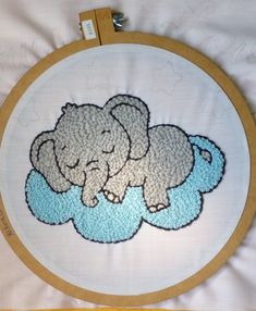 an elephant is laying on top of a cloud in the shape of a cross stitch