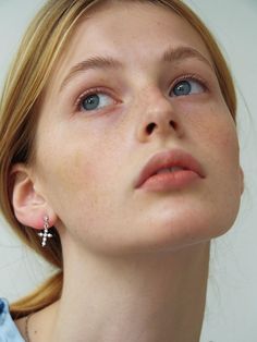 a close up of a woman with blue eyes and piercings on her ears looking upward