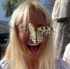 a woman laughing with a butterfly on her face in front of her eyes and mouth wide open