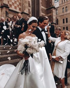 the bride and groom are walking down the stairs with their guests throwing petals in the air