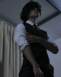 a man with black hair wearing a white shirt and tie is standing in front of curtains