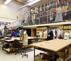 an open room with lots of clothes hanging on the wall and tables in front of them