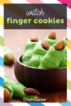 a wooden bowl filled with green cookies covered in frosting and nuts on top of a table