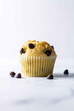 a blueberry muffin with chocolate chips on the side, sitting on a white surface