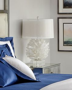 a bed with blue sheets and white pillows in a bedroom next to pictures on the wall