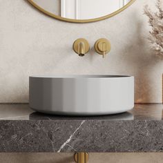 a bathroom sink sitting on top of a counter next to a mirror and vase with flowers