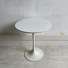 a white table sitting on top of a floor next to a wall and a window