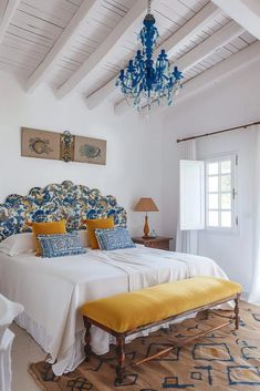 a bed sitting under a blue chandelier next to a white wall and ceiling