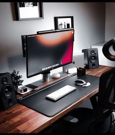 a desktop computer sitting on top of a wooden desk next to speakers and a phone