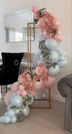 balloons and flowers are arranged in the shape of a spiral on a table next to a chair