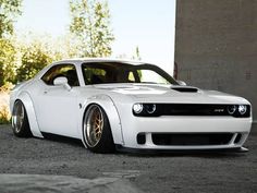 a white sports car parked in front of a concrete structure with trees and bushes behind it