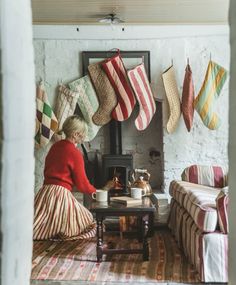 a woman sitting in front of a fire place with stockings hanging from the wall above her