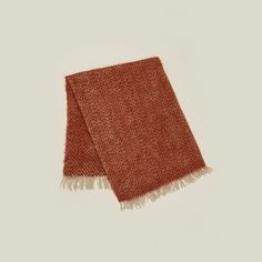 an orange and white scarf with fringes on the ends, laying flat against a white background