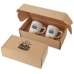 two coffee mugs sitting in a box next to each other