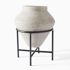 a white vase sitting on top of a metal stand